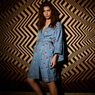 Full front view of light blue denim robe with red floral embroidery, deep V-neck, and kimono sleeves, unbelted