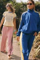 Two models walking wearing Atmosea blush pink Après Surf Panel Pants with side panel detail