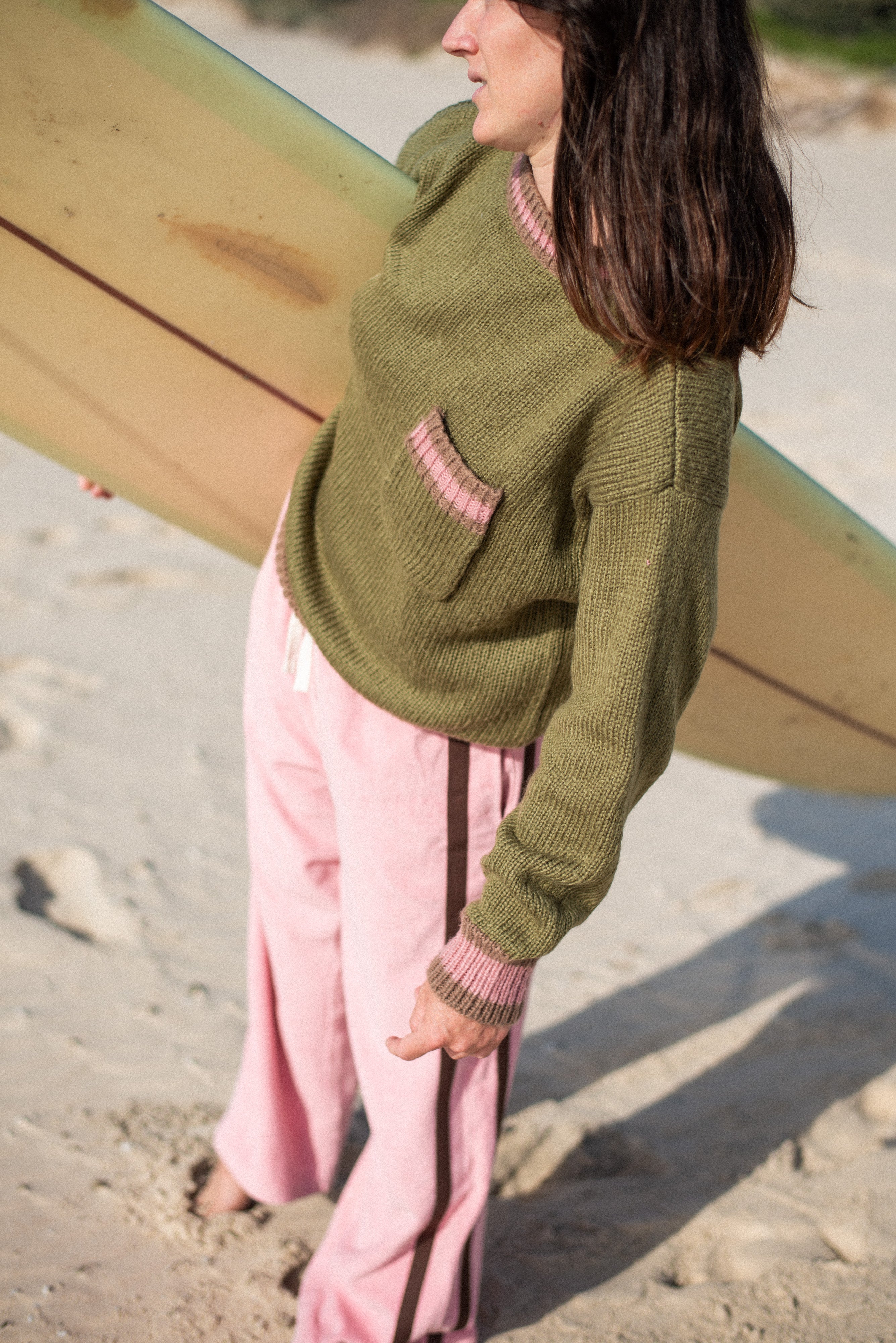 Beach lifestyle shot highlighting blush pink Après Surf Panel Pants with surfboard background