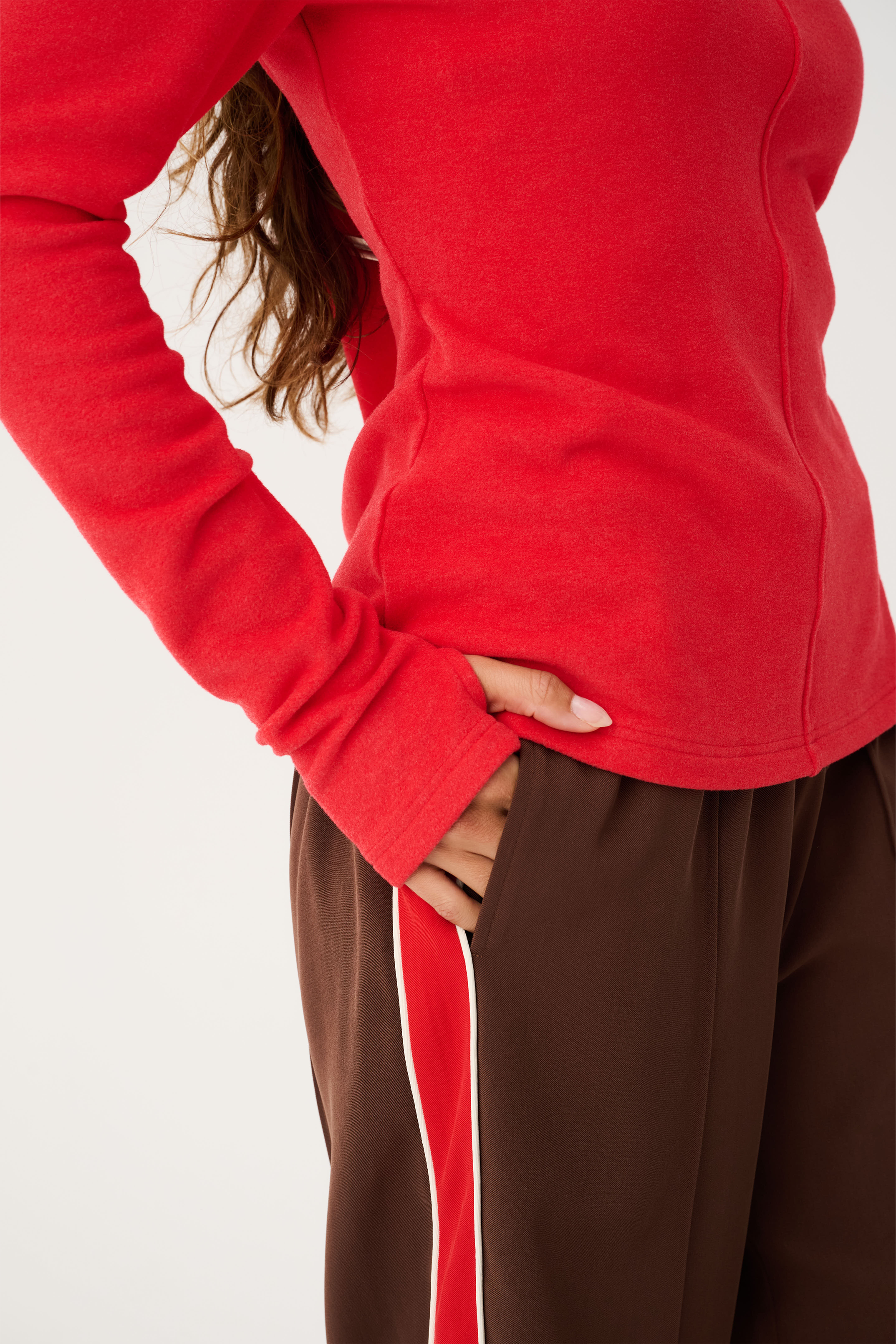 Side view of red Aspyn Top Siren showing fitted silhouette and center seam detail with long sleeves