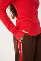 Side view of red Aspyn Top Siren showing fitted silhouette and center seam detail with long sleeves