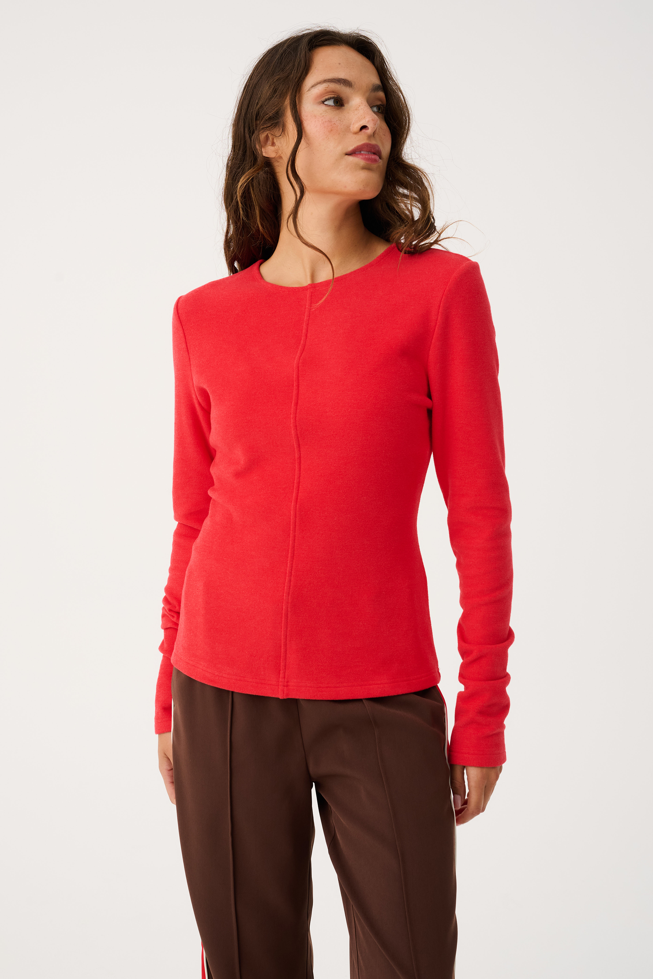 Three-quarter angle view of red Aspyn Top Siren showing fitted long sleeve design and tailored fit