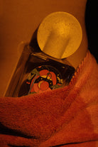 Close-up of Bain De Minuit perfume nestled in coral textured towel with speckled cap visible