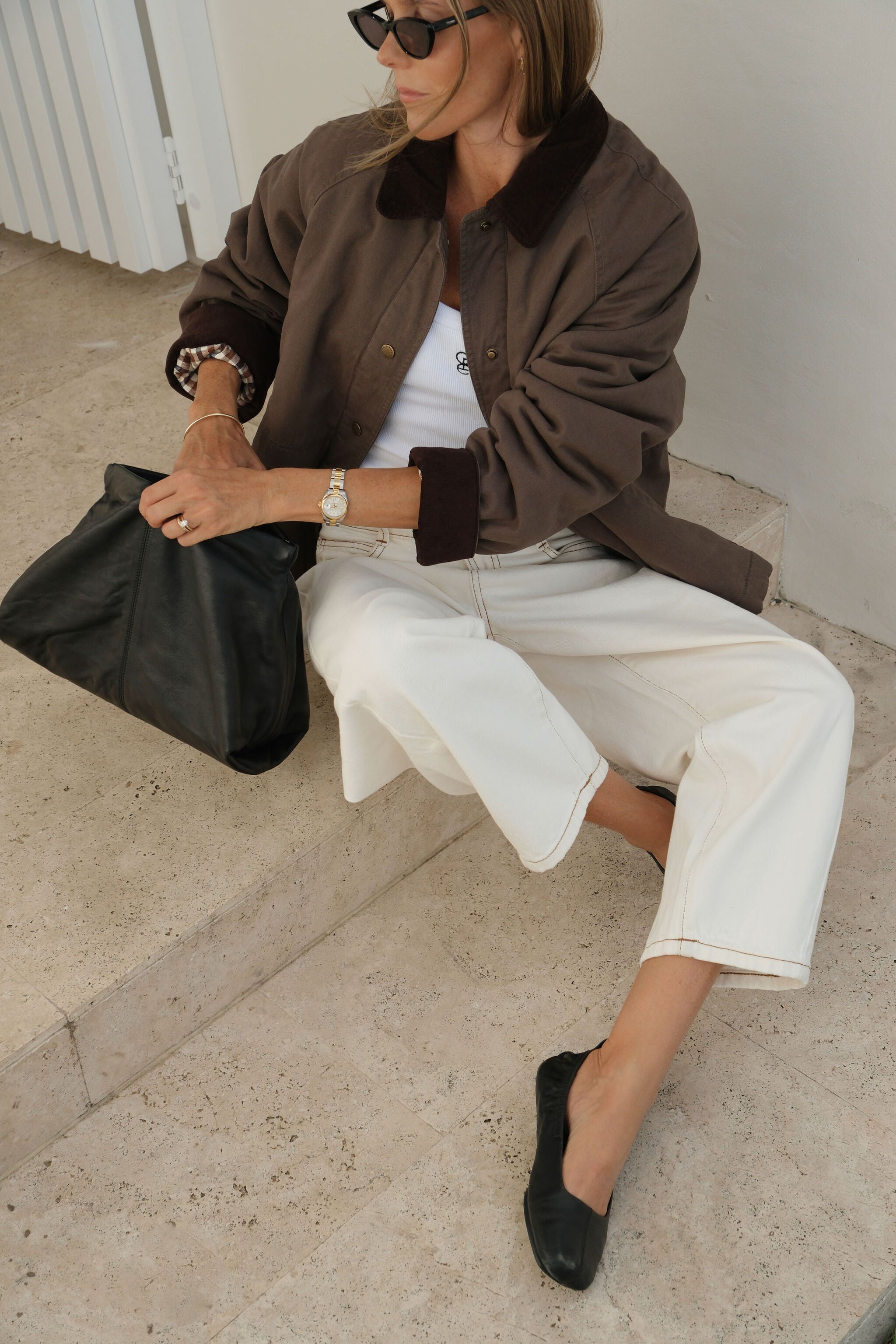 Woman sitting wearing moss green barn jacket with oversized fit and corduroy trim details