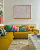 Blue Robin velvet cushion styled on yellow sofa in modern living room setting