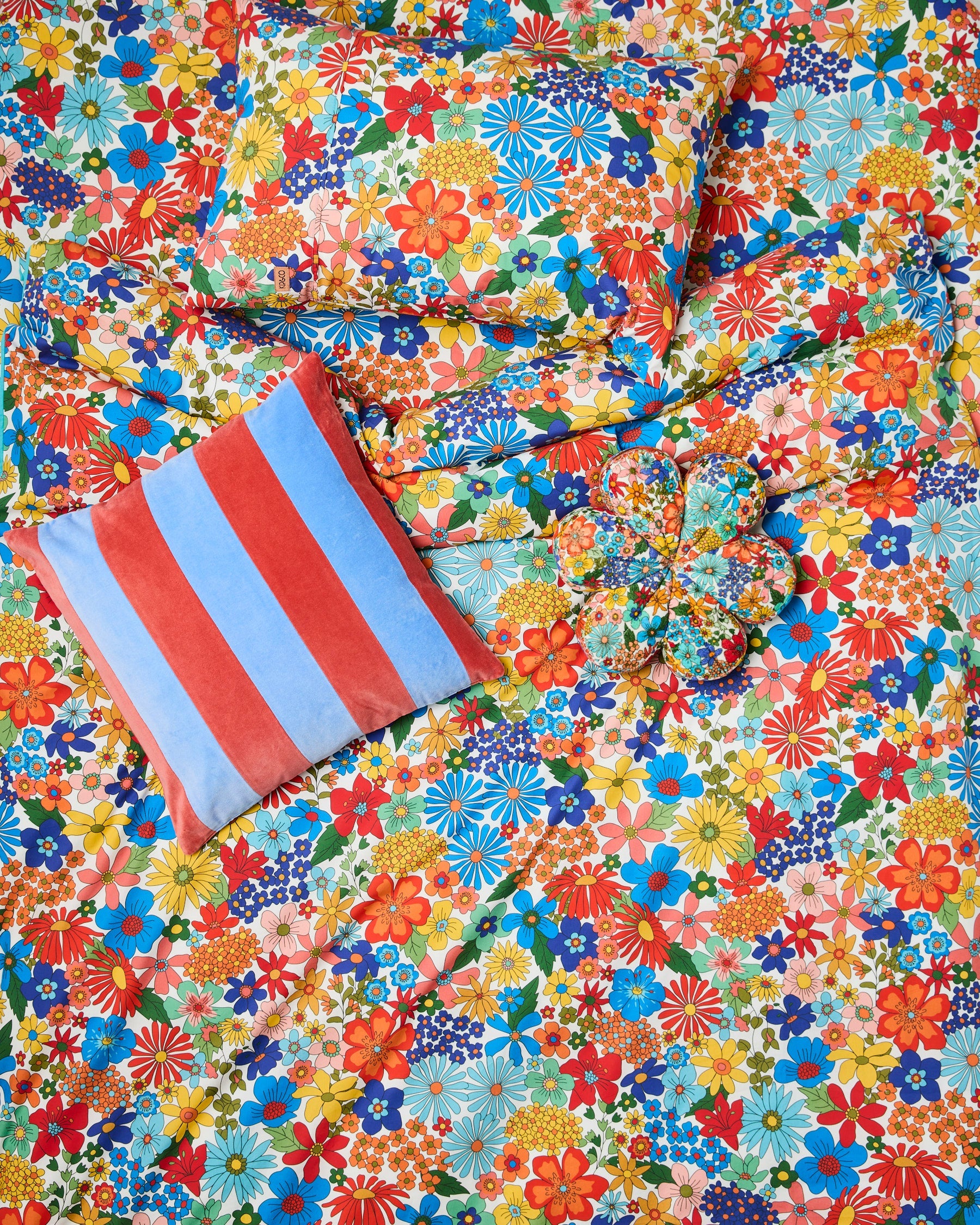 Flat lay of Blue Robin cushion on colorful floral pattern background