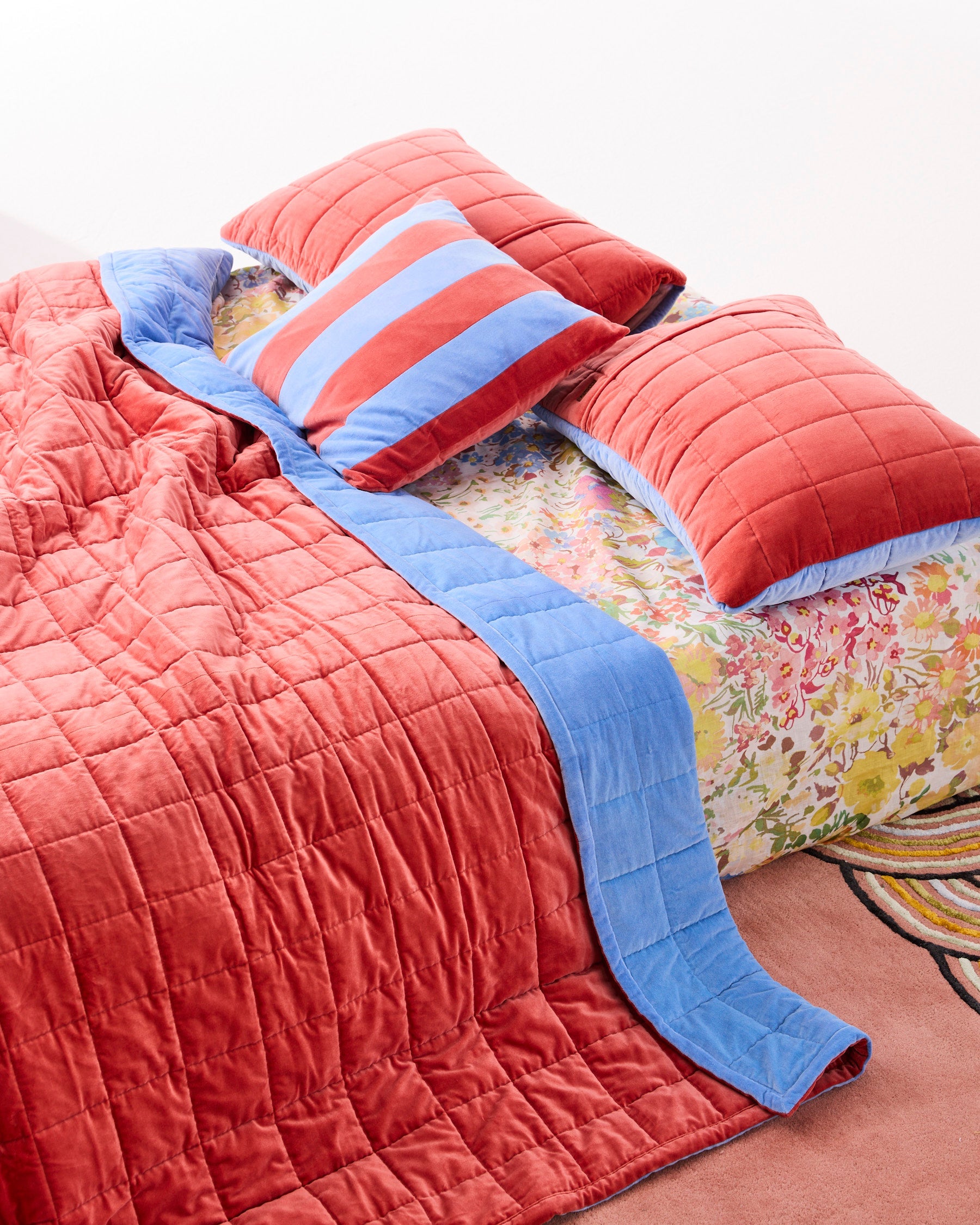 Blue Robin striped velvet cushion styled with matching bedding on bed