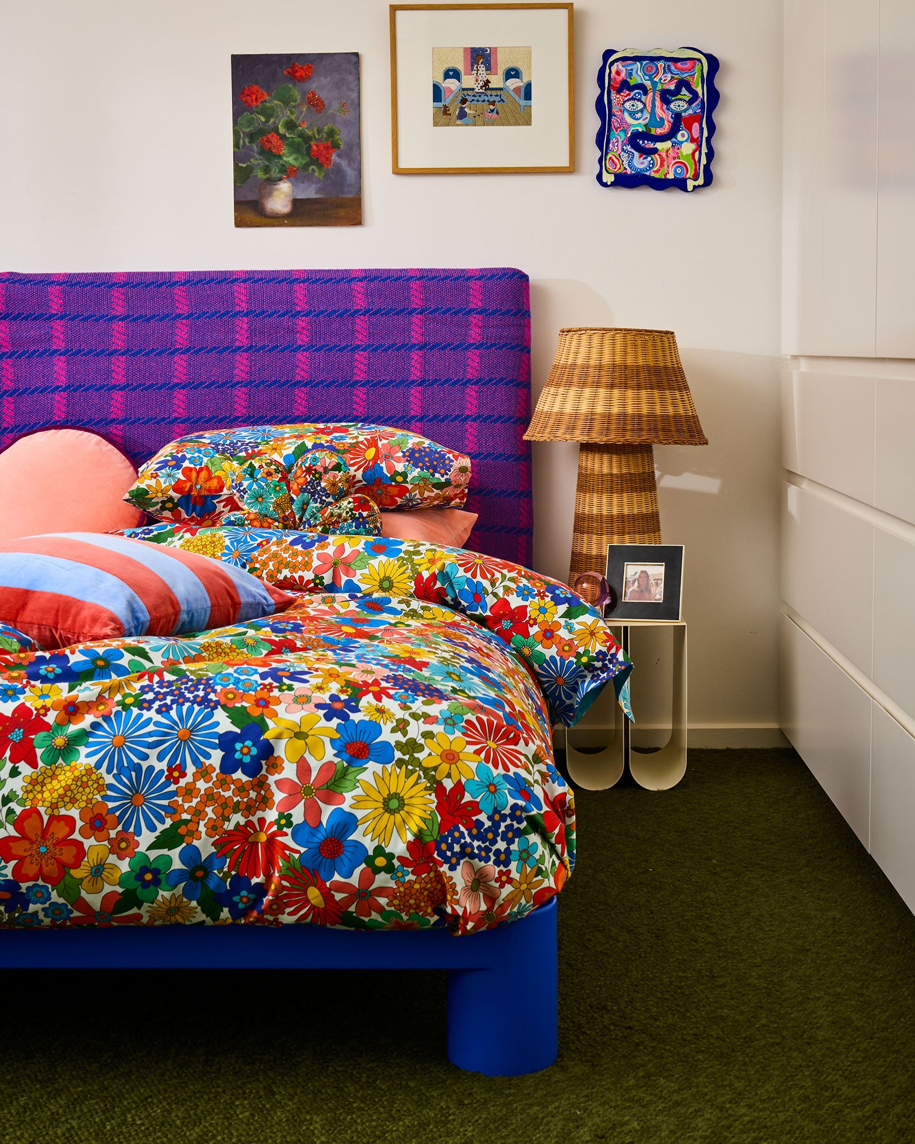 Blue Robin cushion arranged with floral bedding in colorful bedroom styling