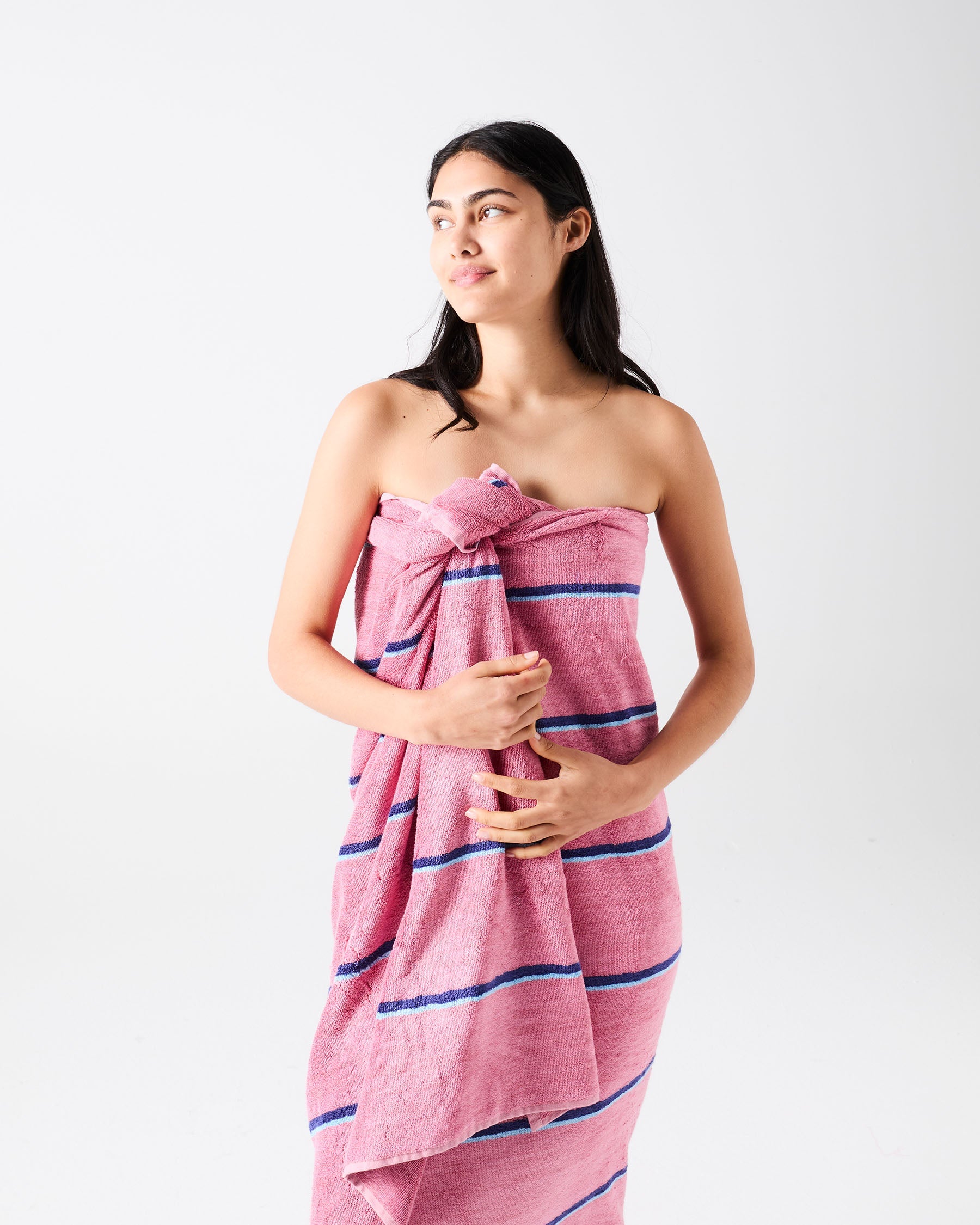 Model wrapped in Blushing Stripe bamboo terry bath sheet showcasing pink striped pattern and soft terry texture