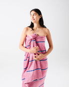 Model wrapped in Blushing Stripe bamboo terry bath sheet showcasing pink striped pattern and soft terry texture