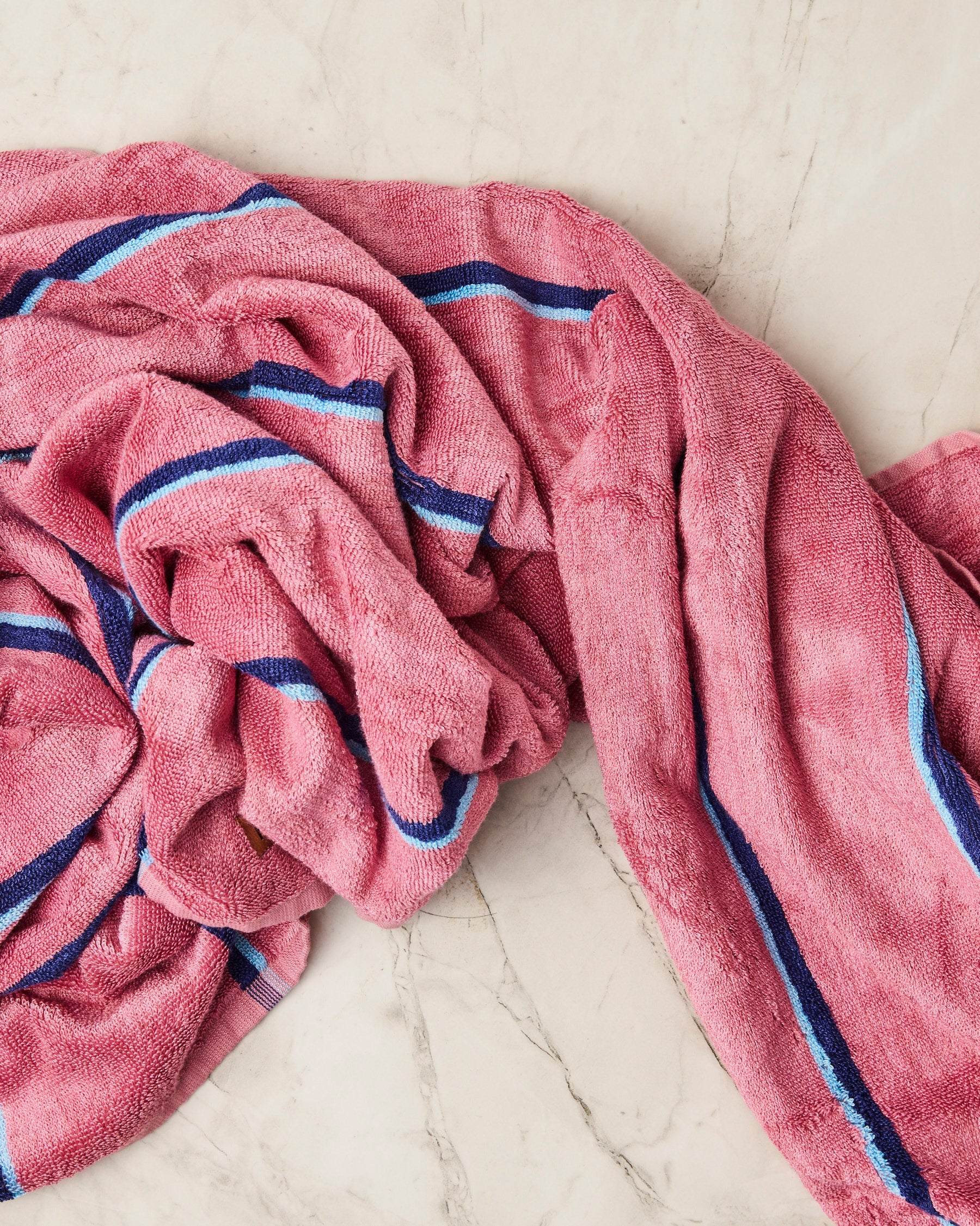 Bunched Blushing Stripe bamboo terry bath sheet on marble surface displaying soft drape and striped design