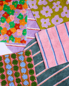 Collection of colorful Kip Co bath mats showing Blushing Stripe design with floral and geometric patterns