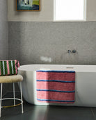 Kip Co Blushing Stripe Bath Mat draped over modern white bathtub in contemporary bathroom setting