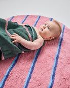 Close-up of baby on Kip & Co Blushing Stripe Bath Mat with green towel showing comfortable texture