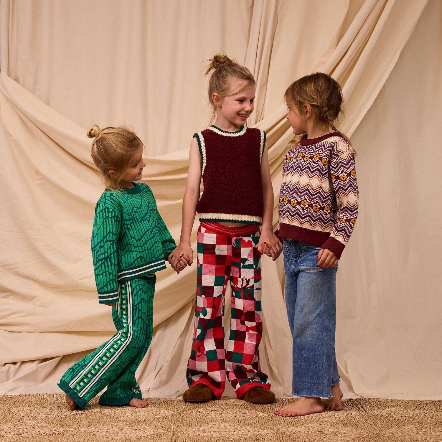Three children modeling different knit outfits with girl in center wearing checkered Bodhi Kids knit pants