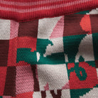 Detail view of checkered knit fabric texture showing red pink green white pattern on Bodhi Kids pants