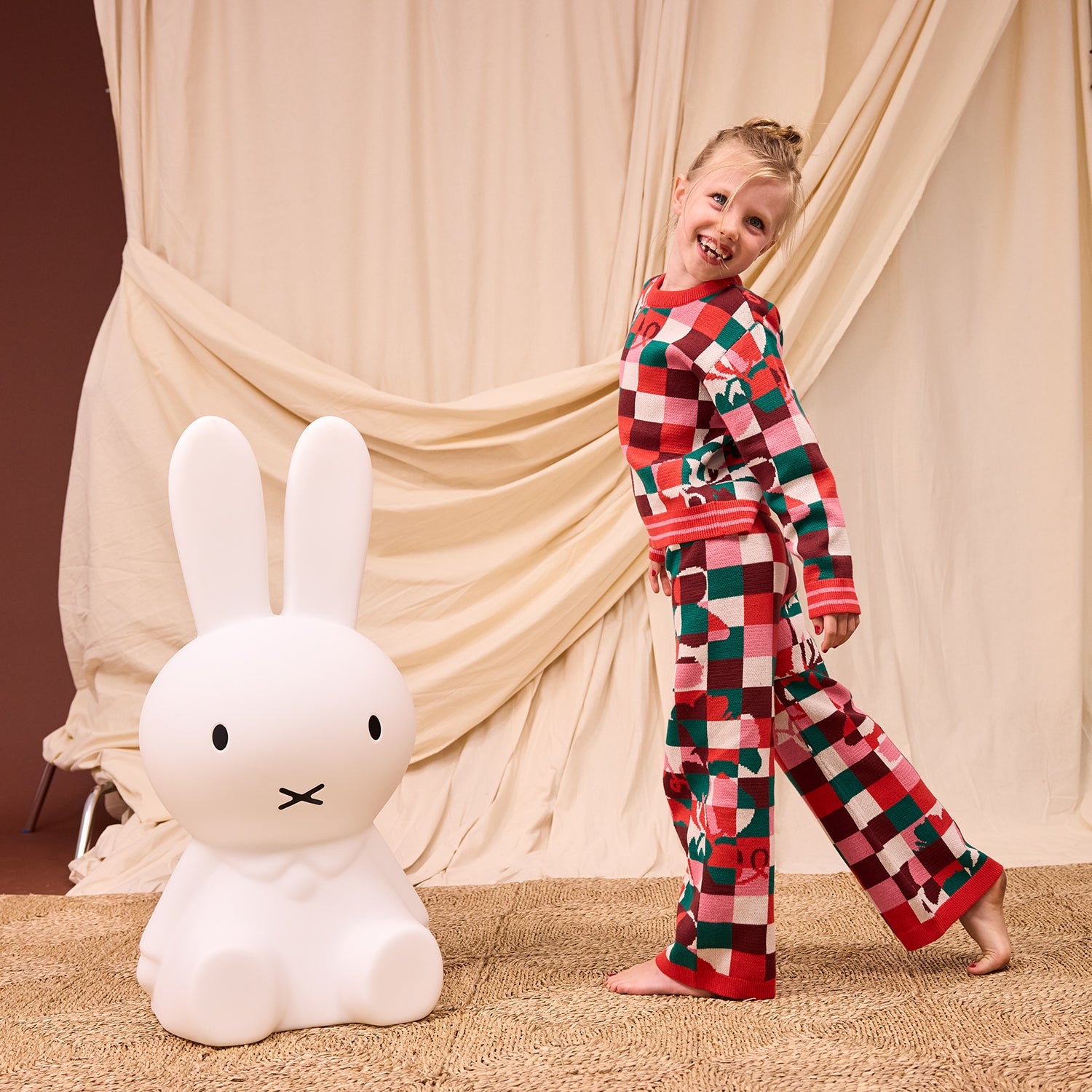Child in Bodhi Kids knit pajamas showing complete colorful checkered sweater and matching pants set