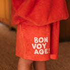 Side angle view of red Bon Voyage Napoli shorts highlighting white text graphics