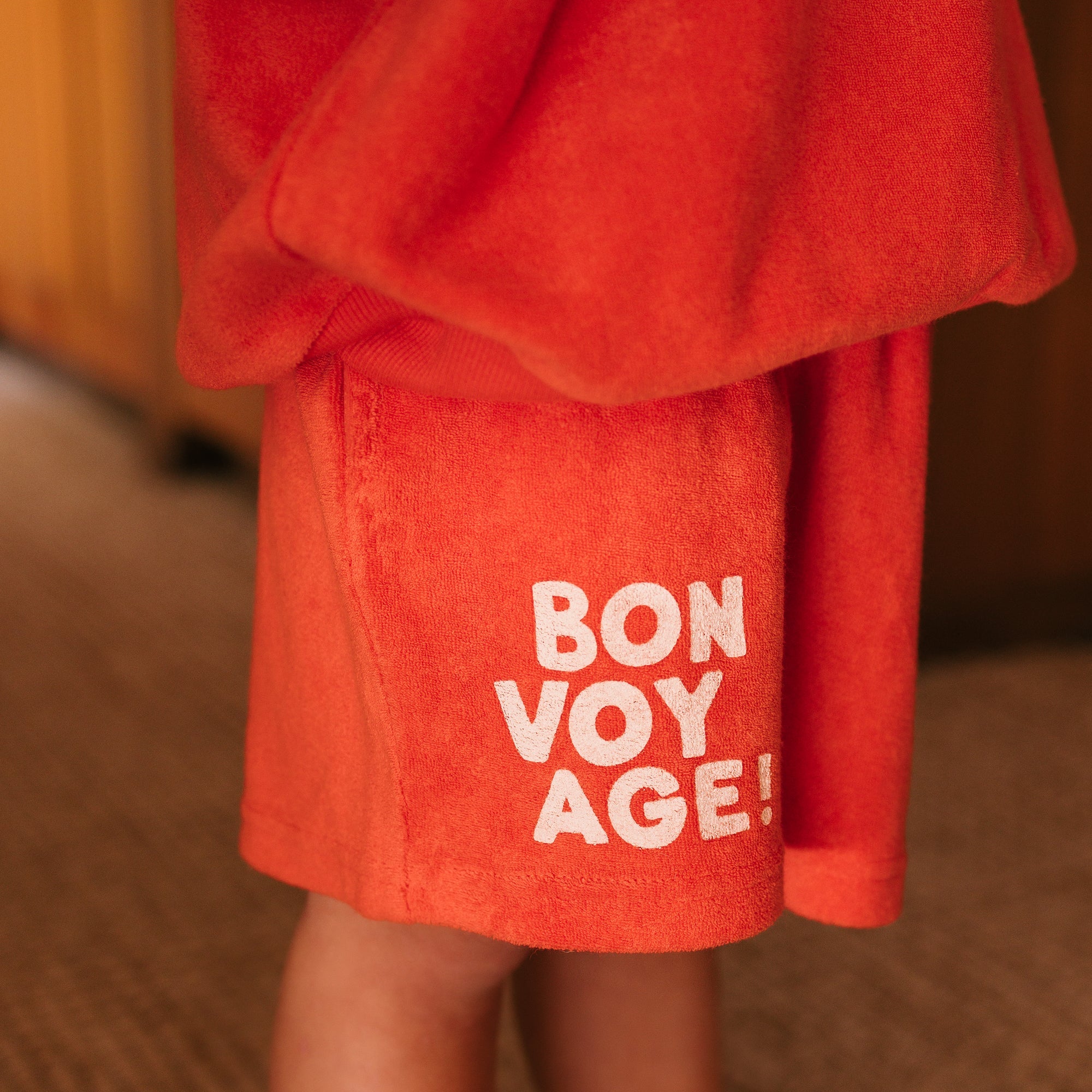 Side angle view of red Bon Voyage Napoli shorts highlighting white text graphics
