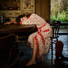 Bonny Cotton Robe in Poppy — full-length view of red and cream floral check print robe on reclining model at table