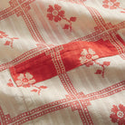 Close-up of Poppy Bonny Cotton Robe fabric showing red floral check print on cream cotton and contrast pocket detail