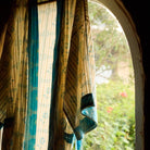 Turquoise Bonny Cotton Robe hanging at an arched window, close-up of floral check print and turquoise cuff trim