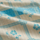 Close-up of Turquoise Bonny Cotton Robe fabric showing turquoise floral check print on cream cotton with pocket detail