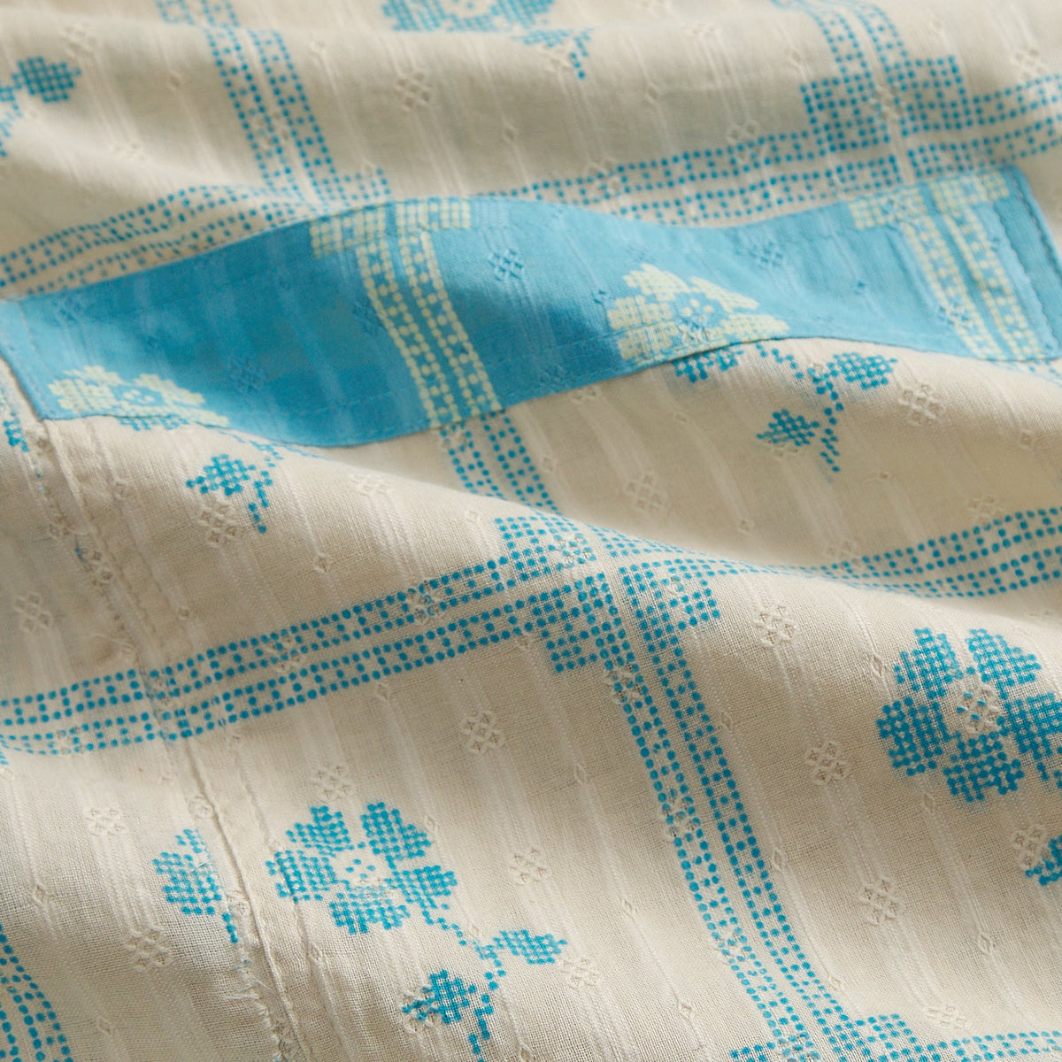 Close-up of Turquoise Bonny Cotton Robe fabric showing turquoise floral check print on cream cotton with pocket detail