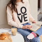 white sweater with black print reading LOVE