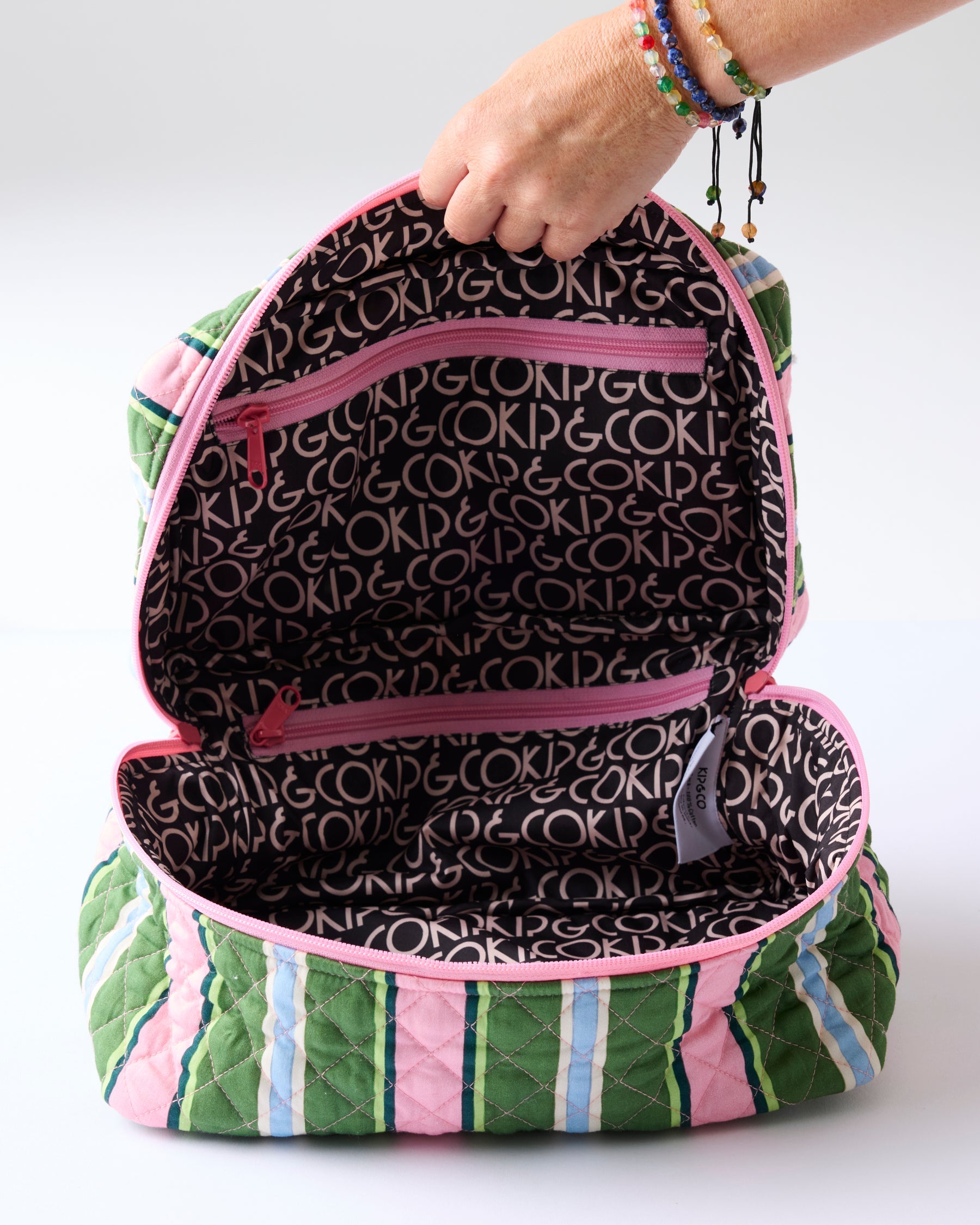 Interior view of Kip & Co Cactus Stripe Toiletry Case showing black logo lining and dual compartment storage