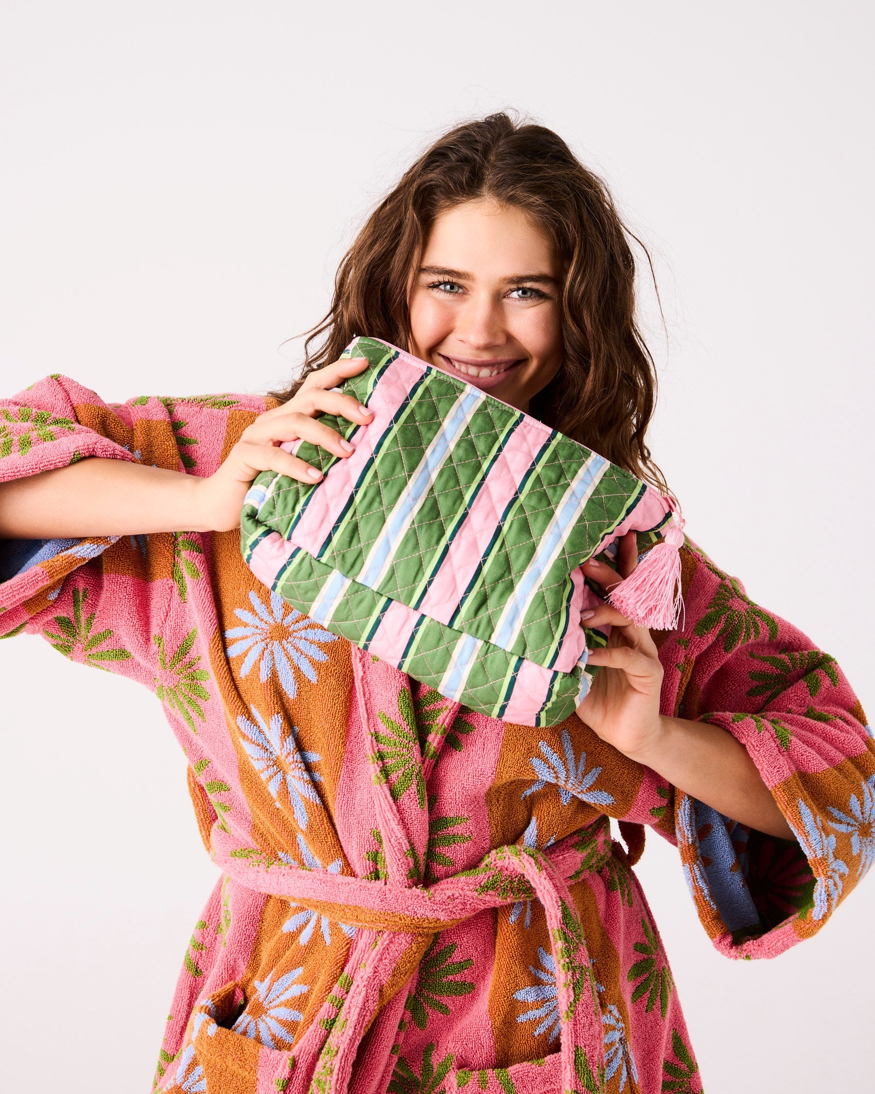Model holding Cactus Stripe Quilted Cotton Toiletry Purse showing green pink blue striped pattern and pink tassel
