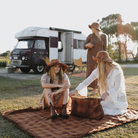 Women enjoying outdoor camping picnic on Camp Picnic Rug by Wandering Folk with vintage caravan
