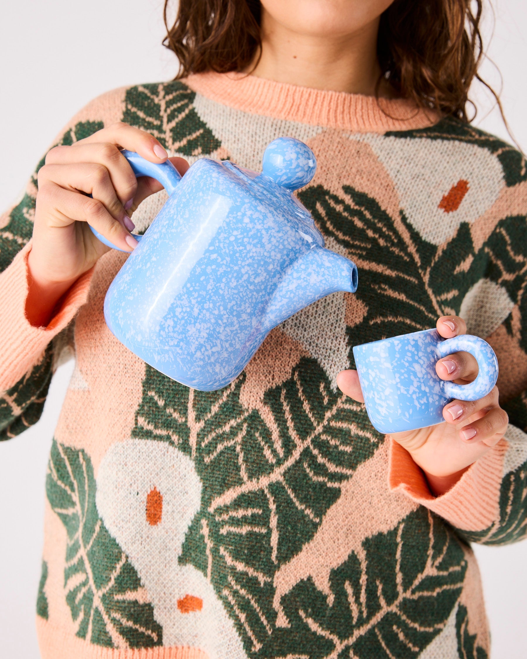 Woman holding blue speckled ceramic teapot and matching espresso mug demonstrating 2P set