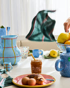 Blue marbled espresso mug in styled kitchen scene with colorful ceramic tableware and fruit