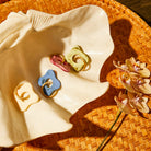 Flat lay of four marble resin flower keyrings in blue pink green and cream displayed on ceramic dish