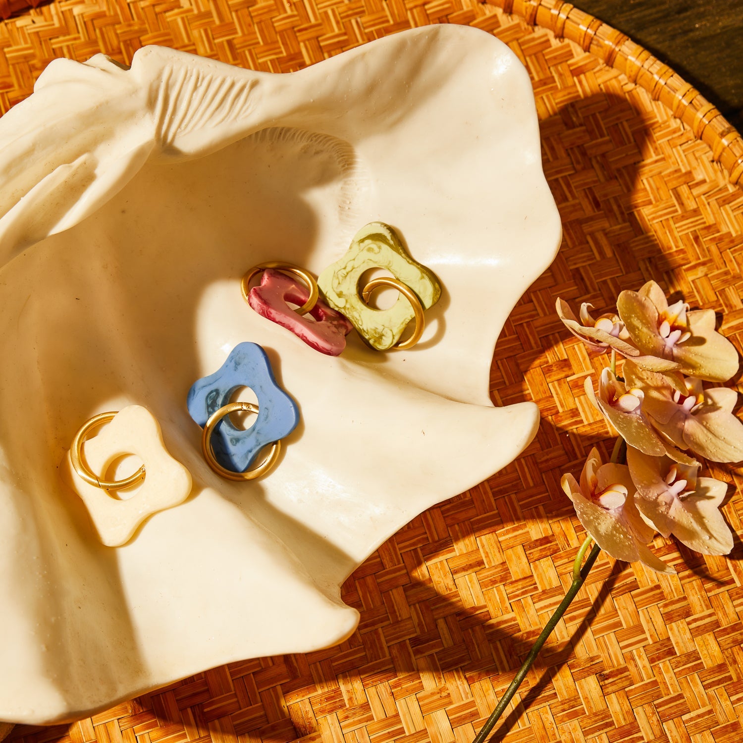 Flat lay of four marble resin flower keyrings in blue pink green and cream displayed on ceramic dish