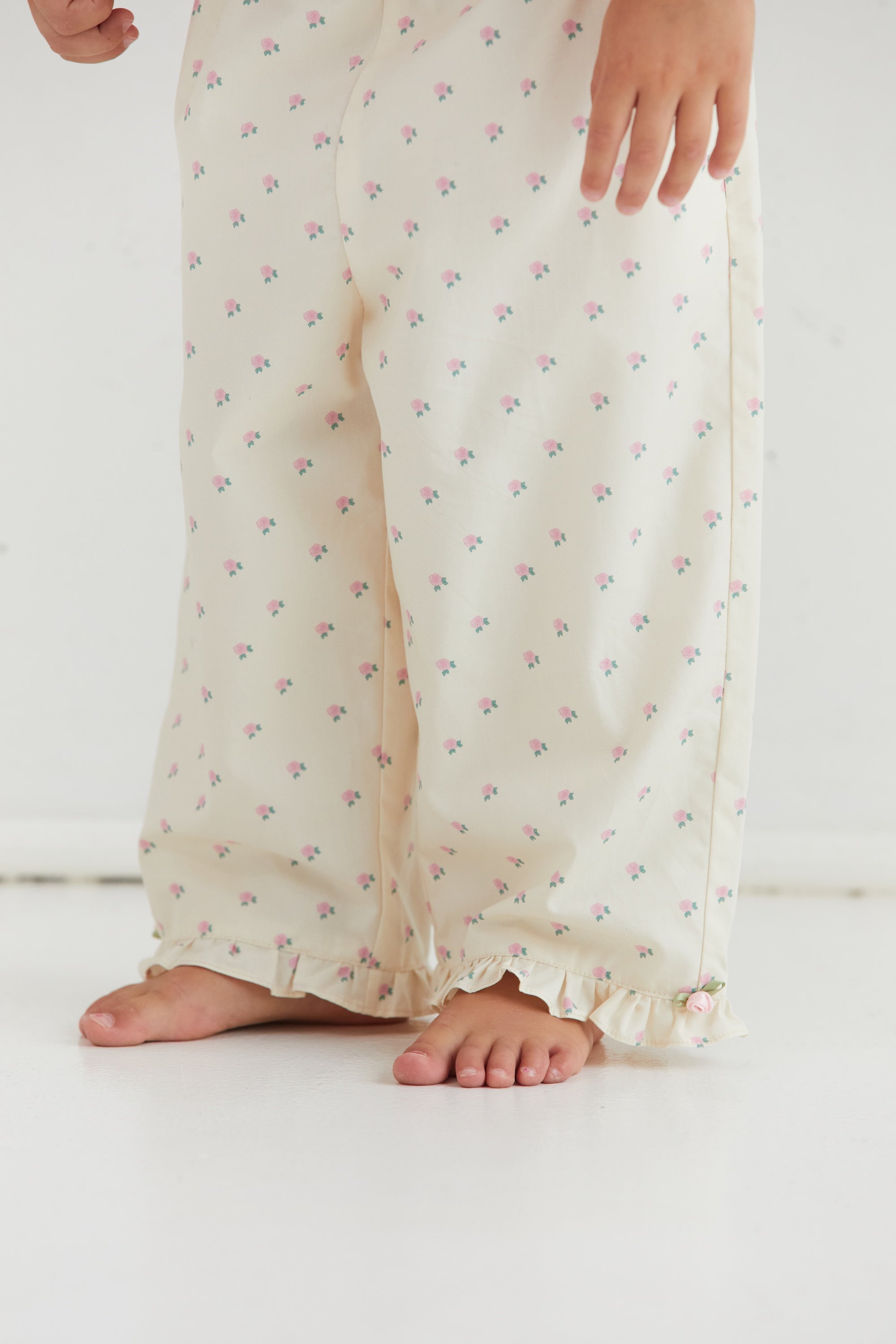 Close-up of Cleo Pant rose pattern fabric and ruffle hem detail from front view