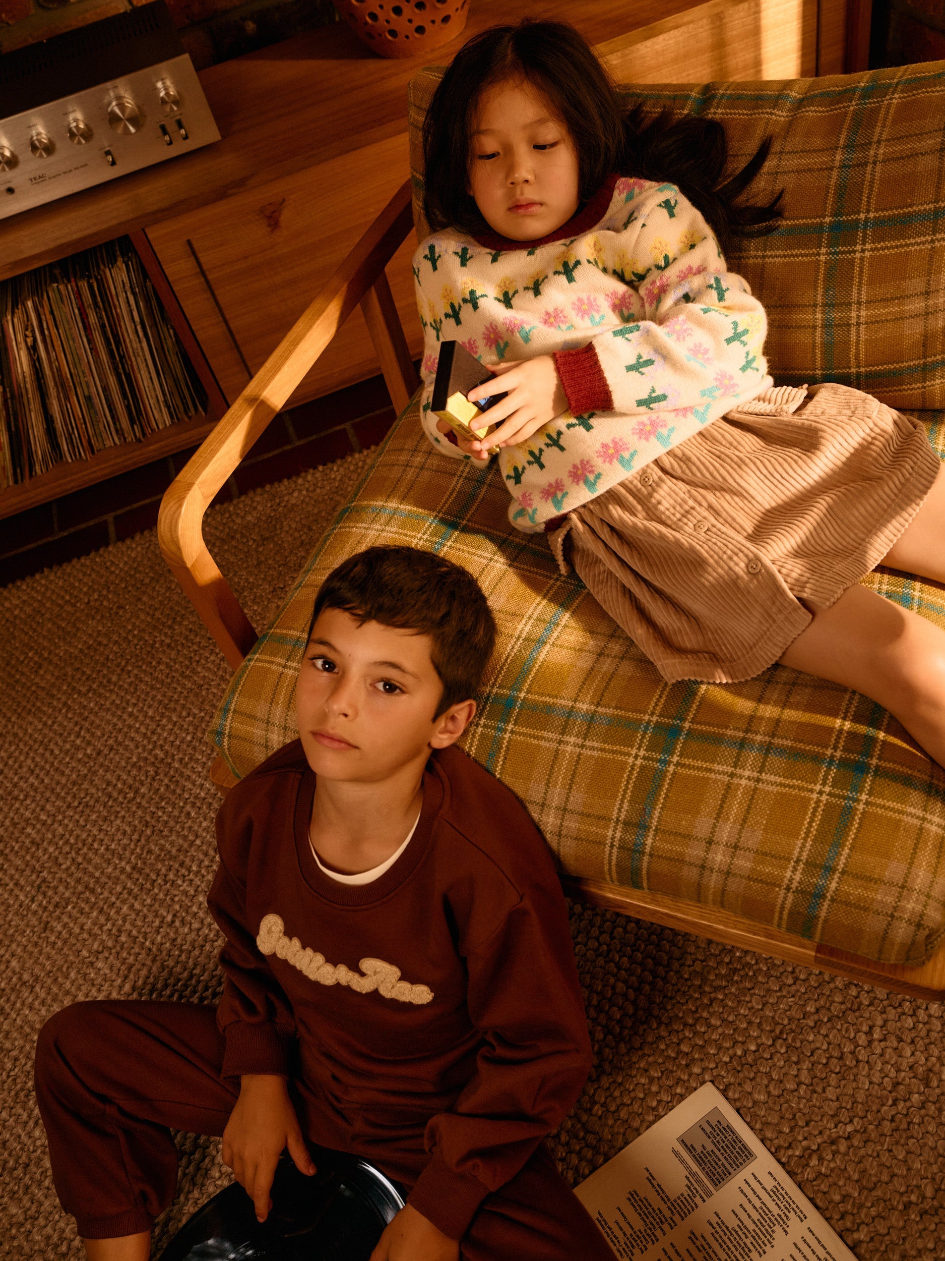 Brown embroidered sweater with long sleeves and crew neck worn casually in living room setting