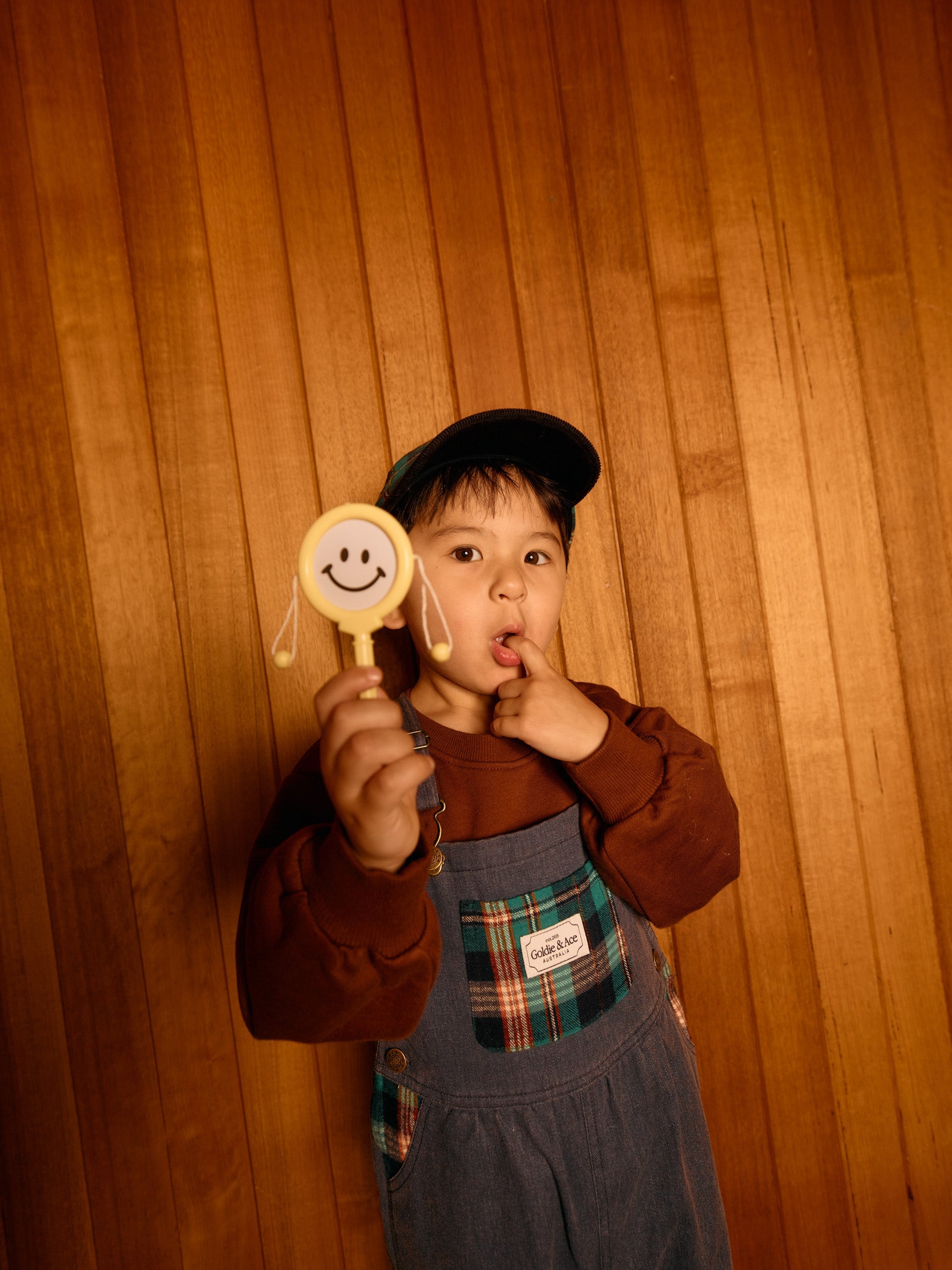 Brown embroidered sweater with long sleeves and golden embroidery worn under denim overalls