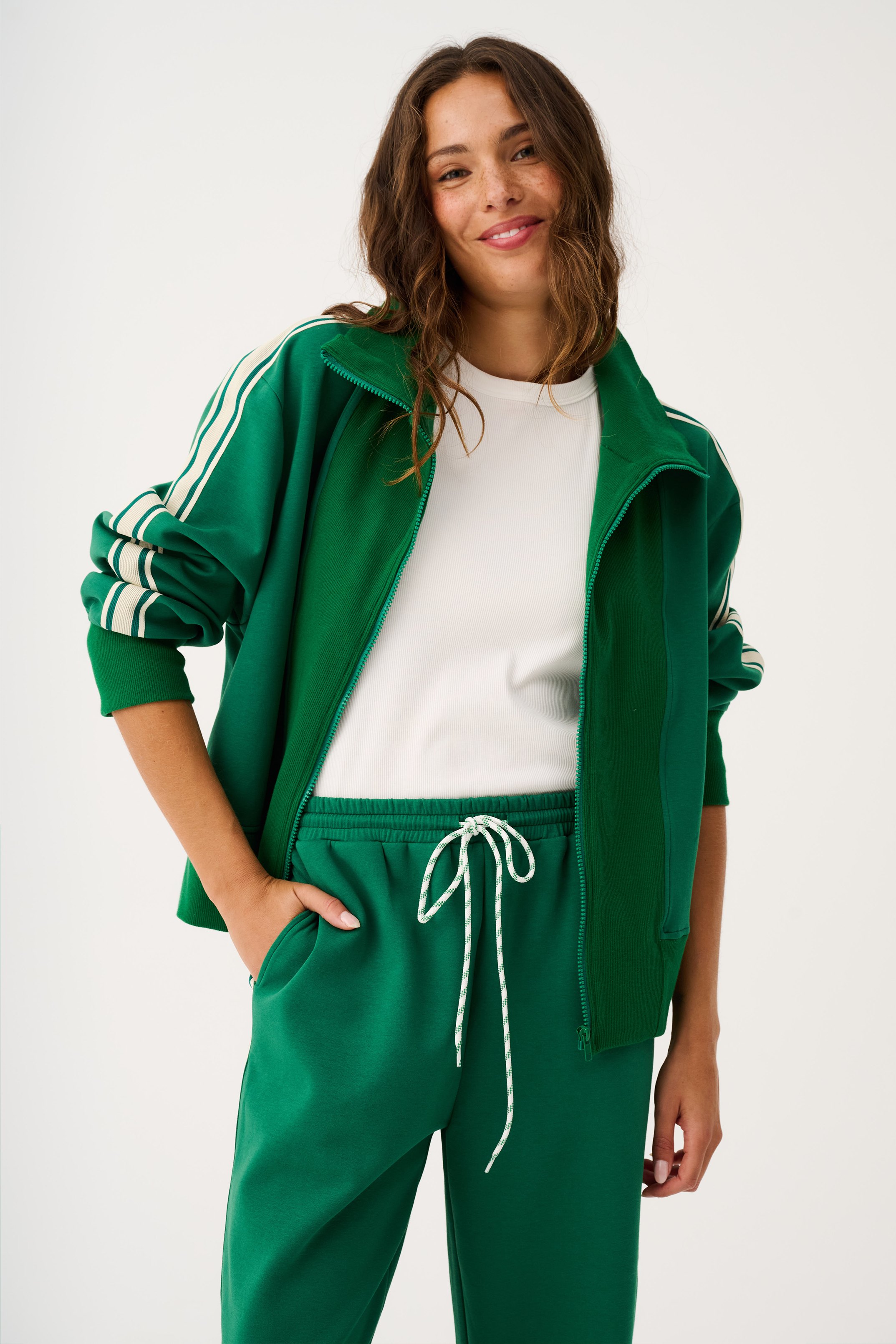 Close-up front view of green zip through sweater showing full zipper closure and striped sleeve details