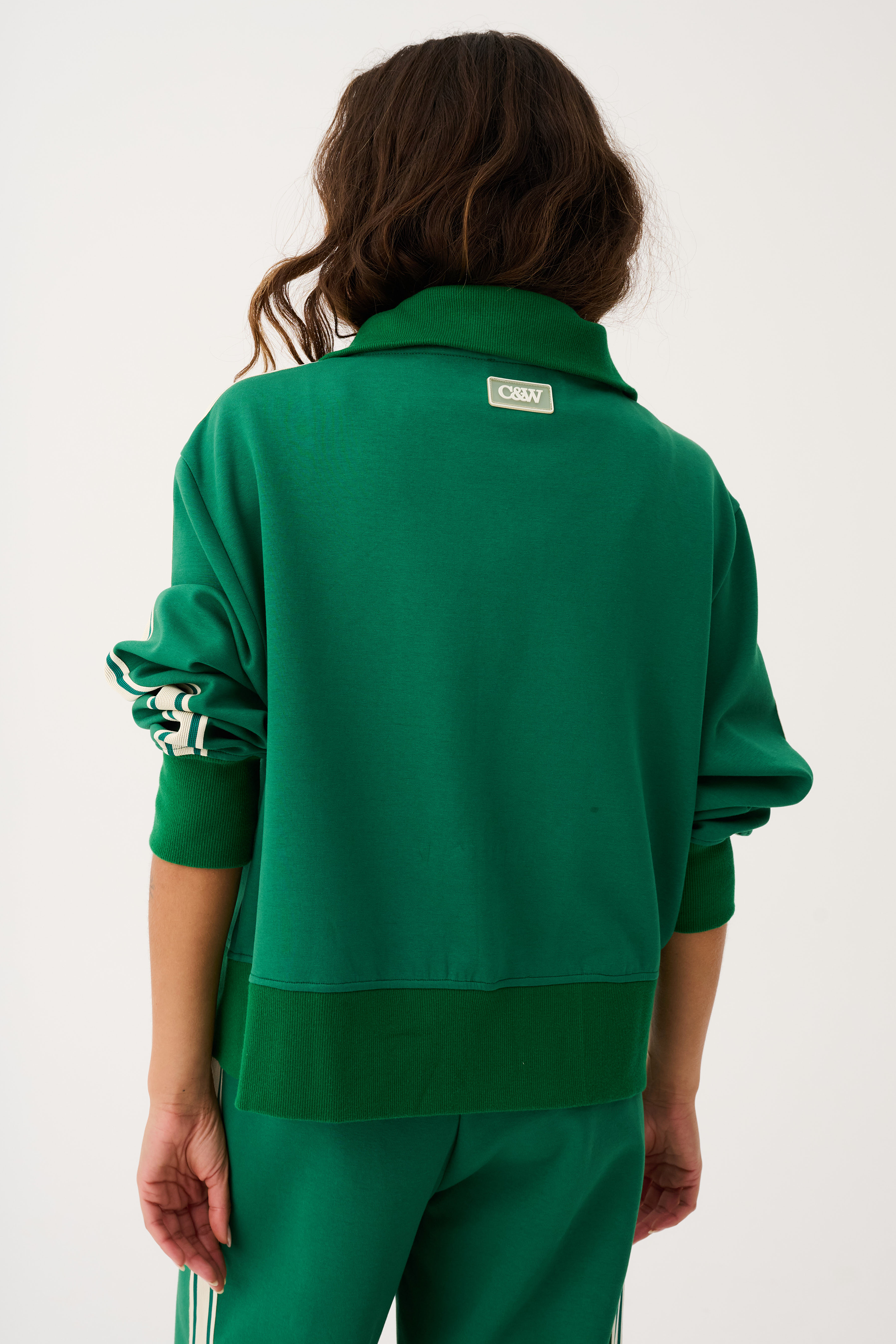 Back view of green Corey sweater displaying brand label and white striped sleeve design