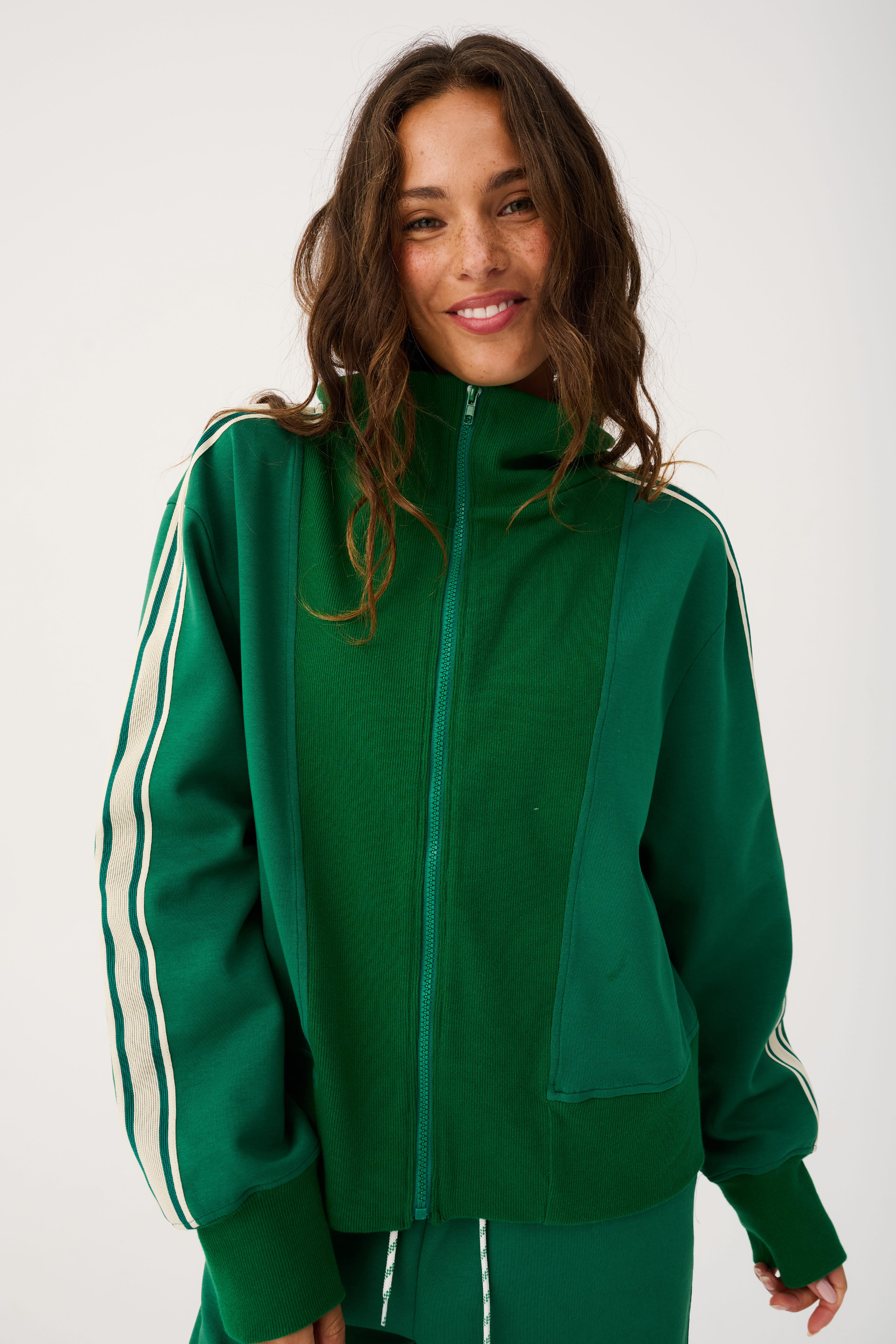 Front detail of green zip up sweater with high collar showing zipper pull and ribbed cuffs