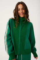 Front detail of green zip up sweater with high collar showing zipper pull and ribbed cuffs