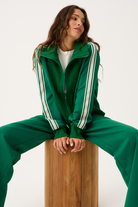 Full tracksuit view of green Corey Zip Through Sweater worn open over white tee with matching pants
