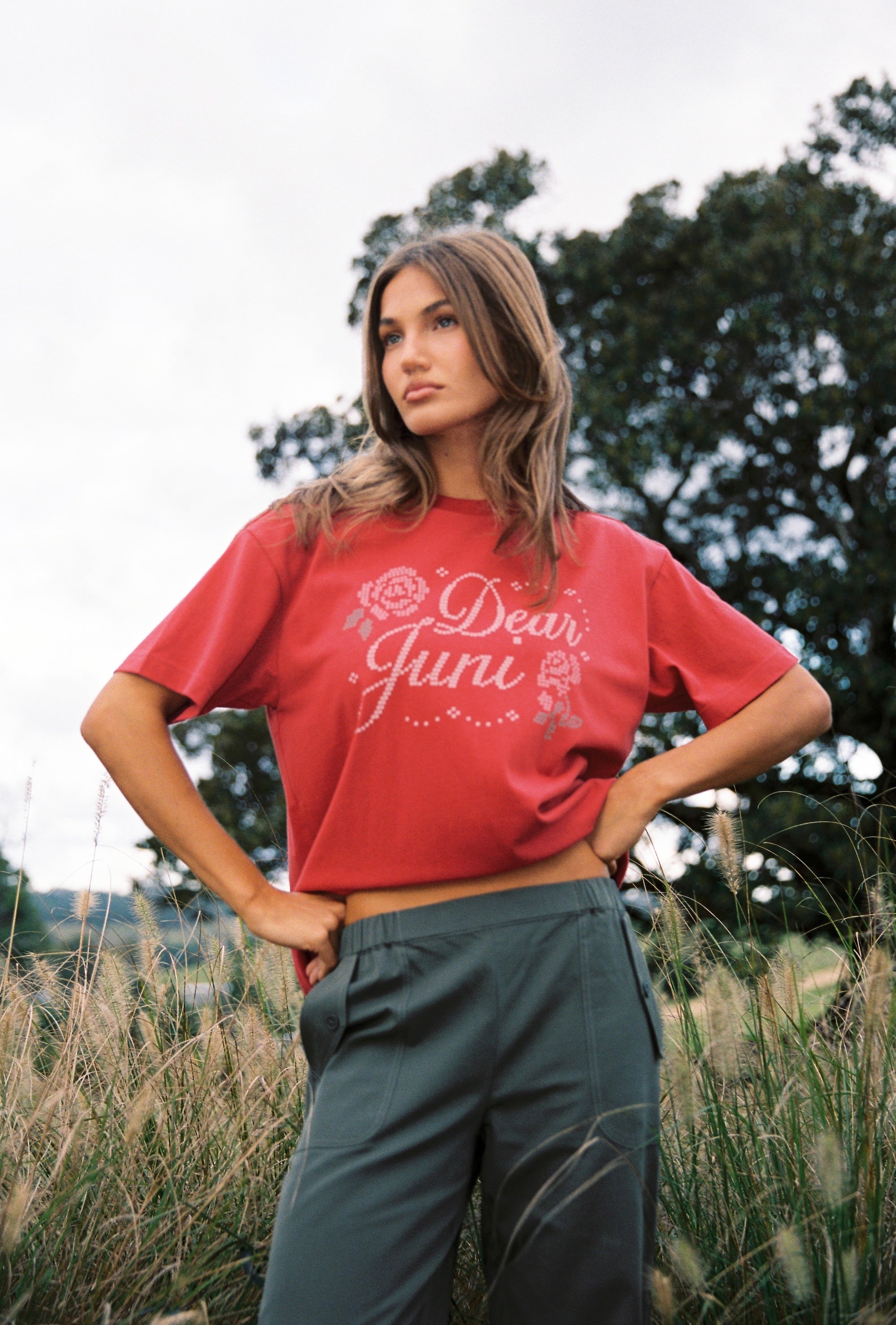 Side angle of red Dear Juni Tee displaying rhinestone embellished lettering and floral motifs