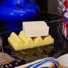 Aspen Gold wave soap dish holding a white bar of soap on a dark marble surface with decorative objects