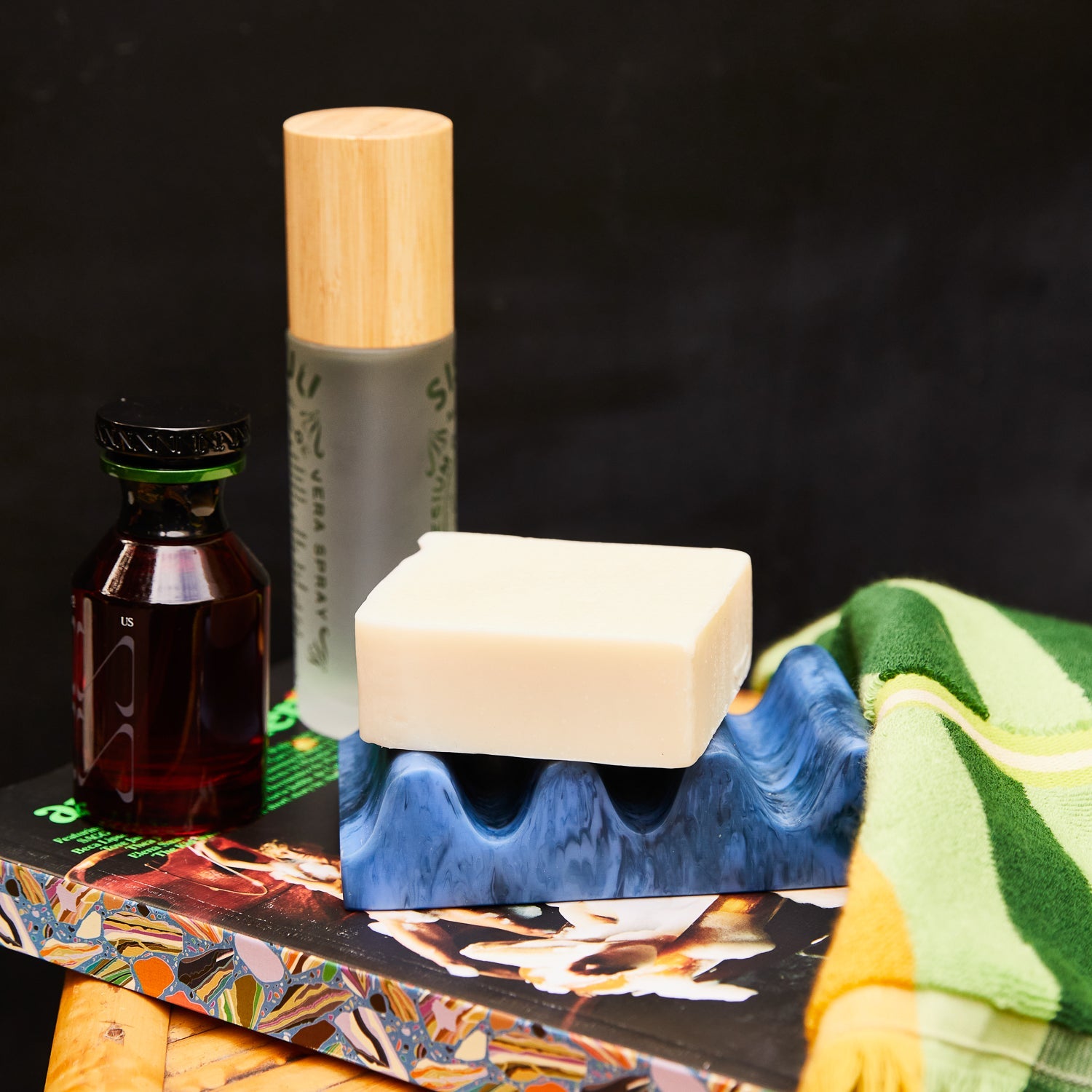 Azure marbled wave soap dish with a bar of soap resting on top, styled with bathroom products on a wooden surface