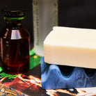 Close-up of Azure marbled wave soap dish with a bar of soap resting on it, styled with apothecary bottles