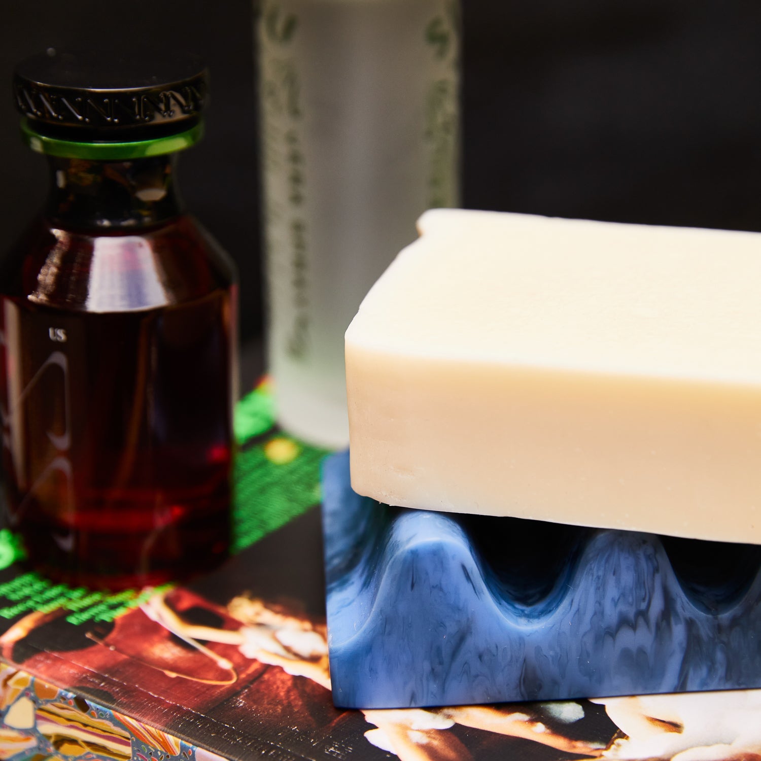 Close-up of Azure marbled wave soap dish with a bar of soap resting on it, styled with apothecary bottles