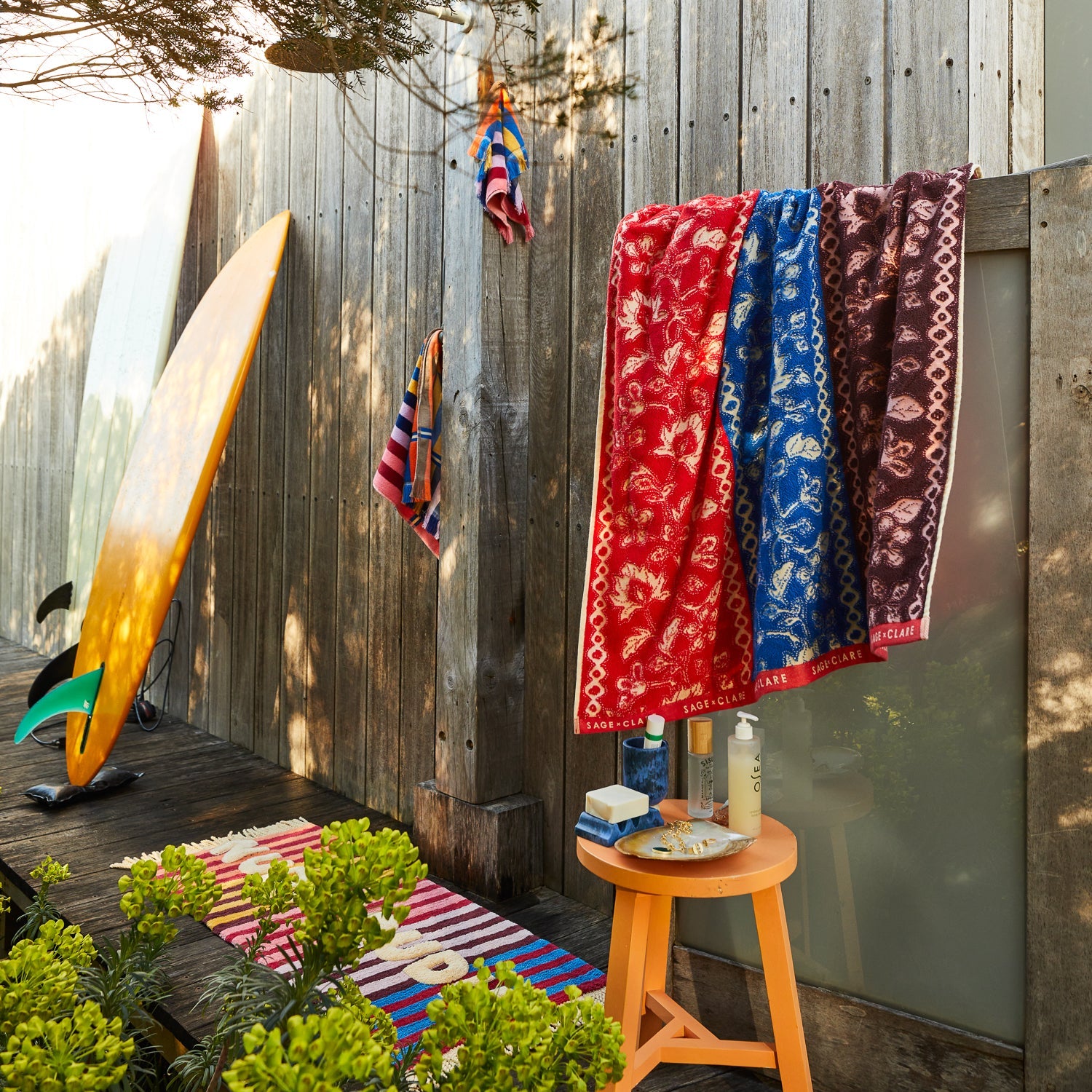 Azure marbled wave soap dish on an orange stool in an outdoor shower setting with colourful towels